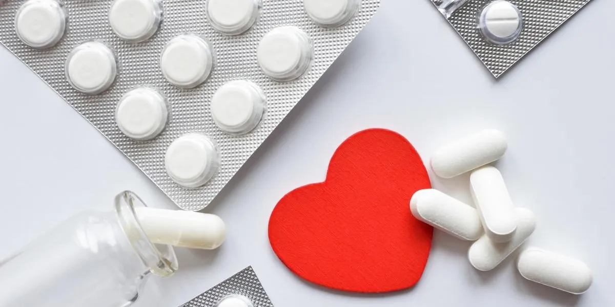 red heart with different packings full of pills over white background, healthy life concept