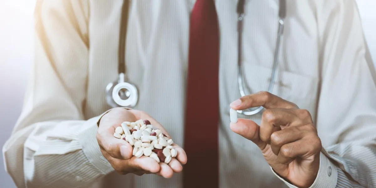 asian male doctor displaying a handful of pills in his palm