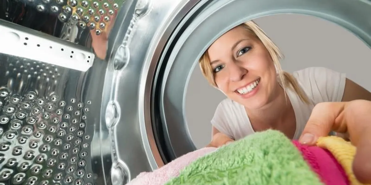 gros plan, de, jeune, femme souriante, insertion, vêtements, dans, machine à laver