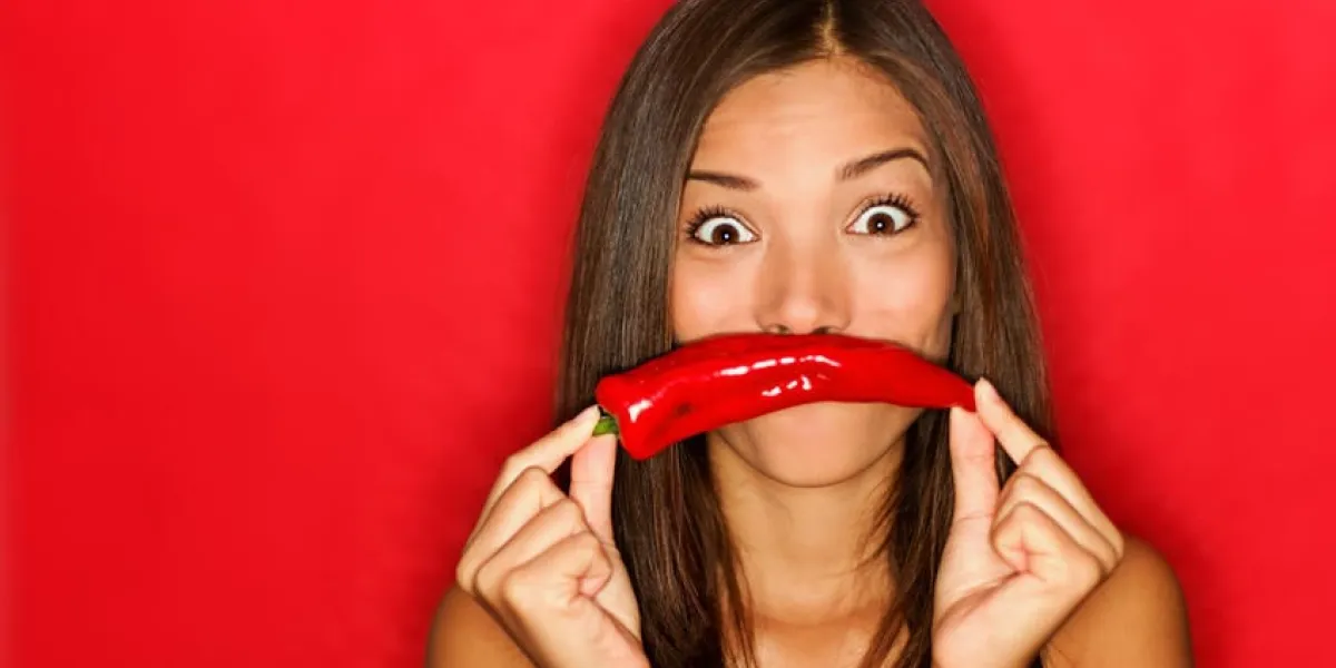 femme chili drôle sur fond rouge tenant des légumes de piment rouge comme la moustache regardant drôle à la caméra belle caucasienne asiatique caucasienne multiculturelle sur fond rouge voir plus