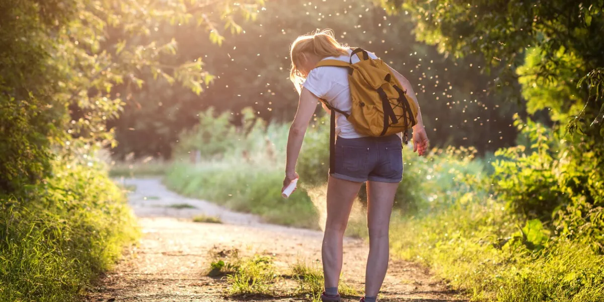 woman applying insect repellent against mosquito and tick on her leg during hike in nature skin protection against insect bite