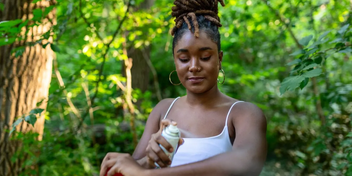 woman applying insect repellent against mosquito and tick on her arms during hike in nature skin protection against insect bite