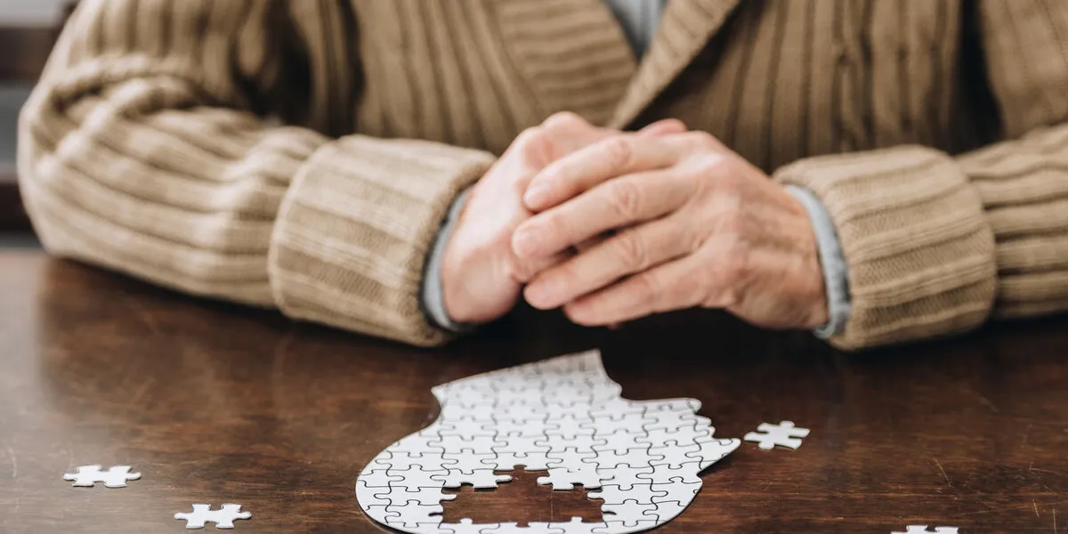 cropped view of senior man playing with puzzles on table