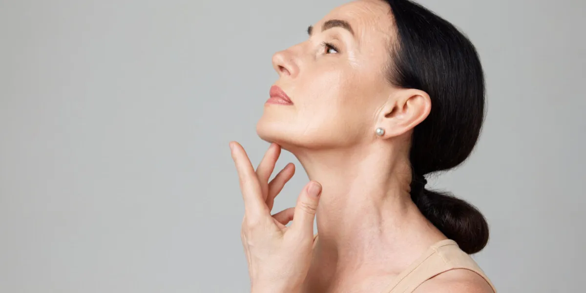 double chin treatment beautiful mature woman touching skin on neck over light grey background copy space for ad concept of fashion, beauty, spa, cosmetology, skin care, procedures