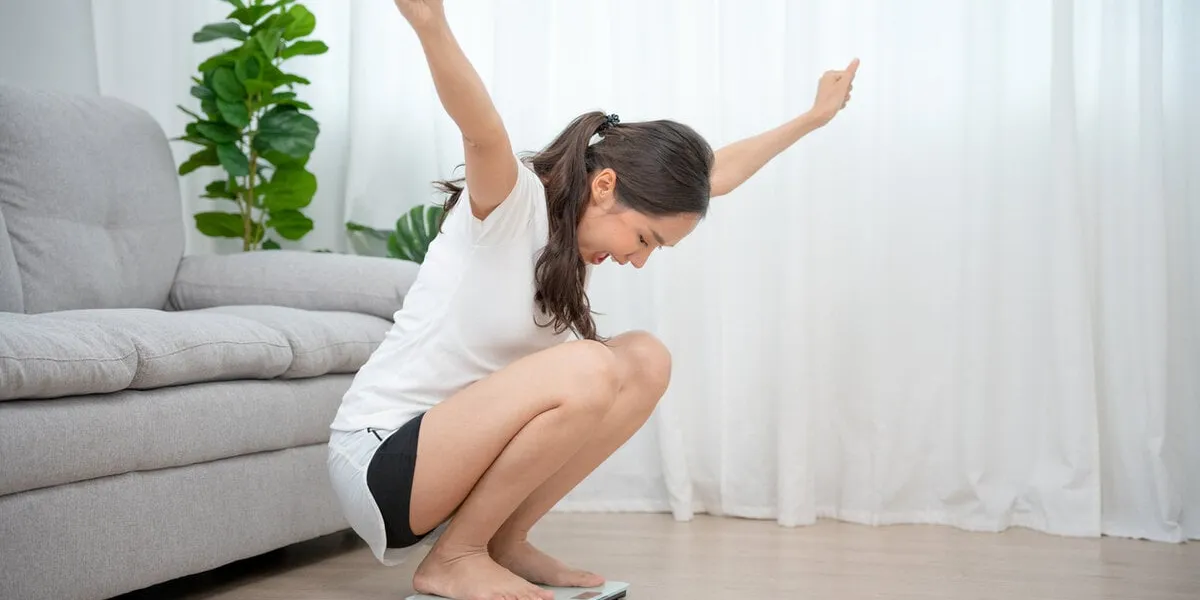 wellness at home diet, dieting woman on weighing scale with happy face expression beautiful asian woman successfully lost weight after joining an exercise and diet plan with a nutritionist