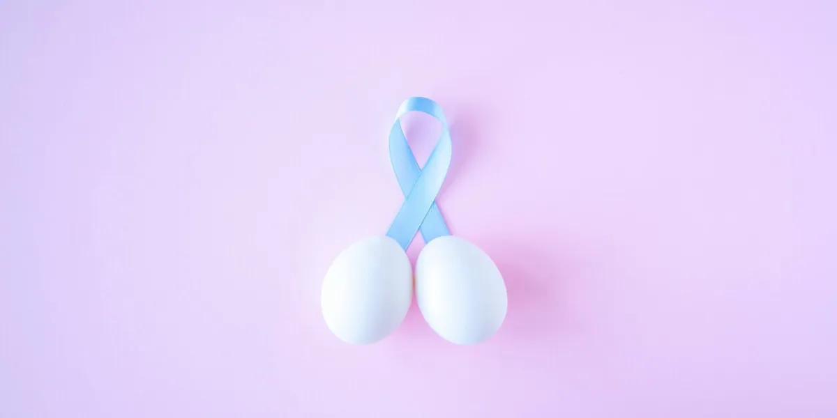 prostate cancer, healthcare, profession, medicine concept - close up of chicken white eggs and blue ribbon in penis shape on bright background cancer awareness, cure, men carcinoma