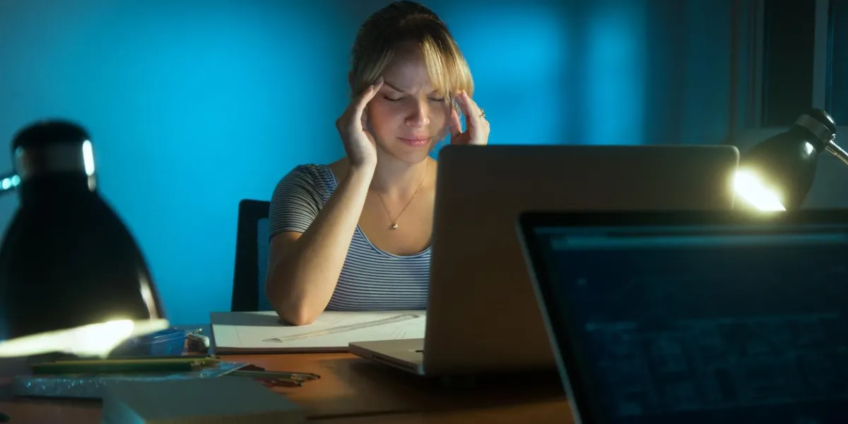belle femme travaillant comme designer d'intérieur, rester tard dans la nuit au bureau avec des dessins et un ordinateur portable la jeune fille se sent fatigué et ses yeux font mal