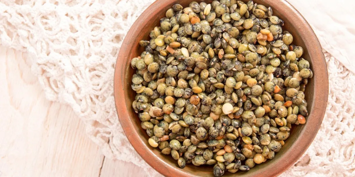 petite assiette avec lentilles vertes organiques crus sur nappe blanche dentelle sur une table en bois blanc