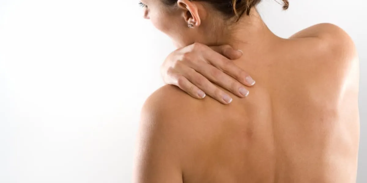 femme par derrière, corps nu, tenant son cou du côté gauche face à gauche