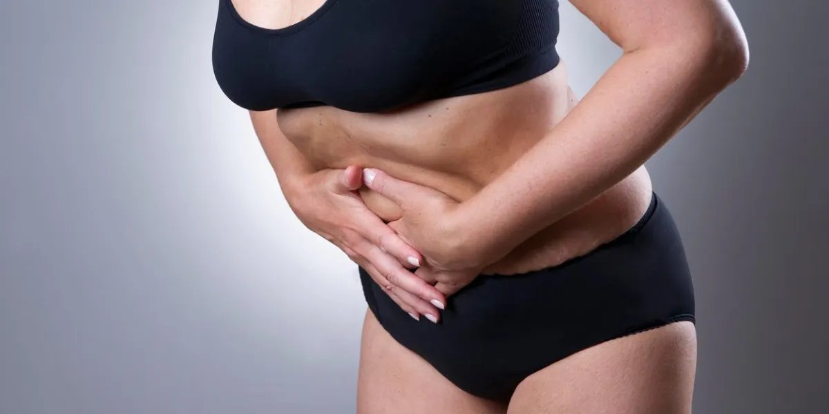 woman with abdominal pain pain in the human body on a gray background