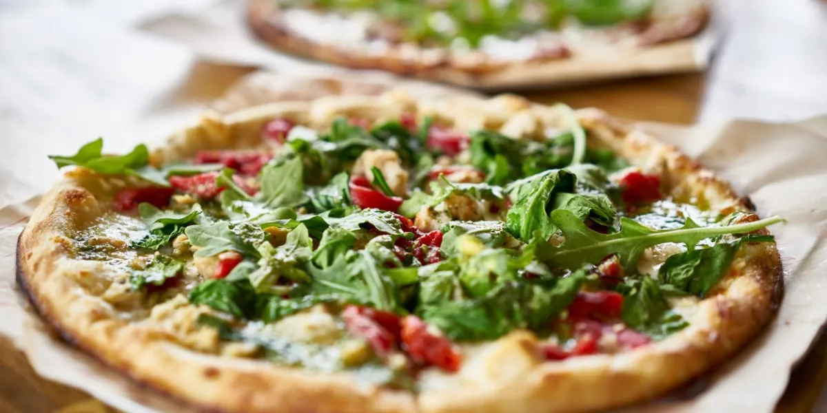 authentic gourmet pizza with fresh arugula, pesto and chicken