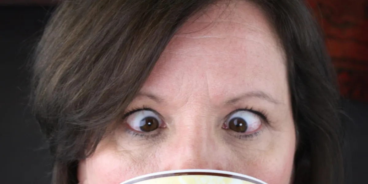 femme regardant dans la tasse de café aux yeux croisés
