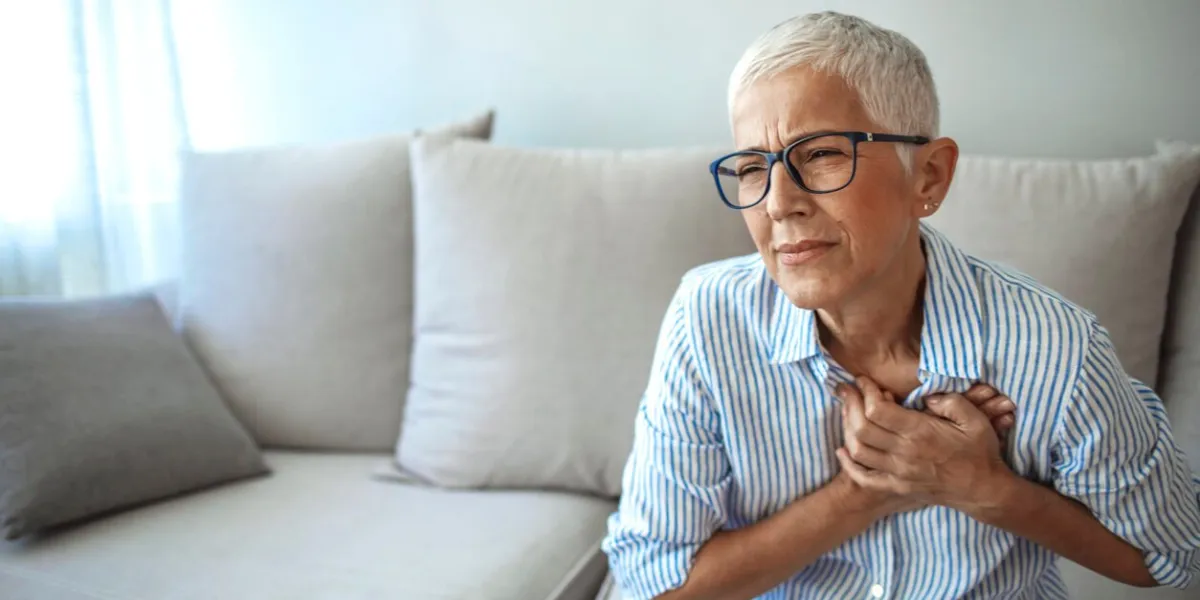 middle age woman wheezing touching chest at home elderly woman having chest pains or heart attack at home woman with heart attack holding and massaging her chest