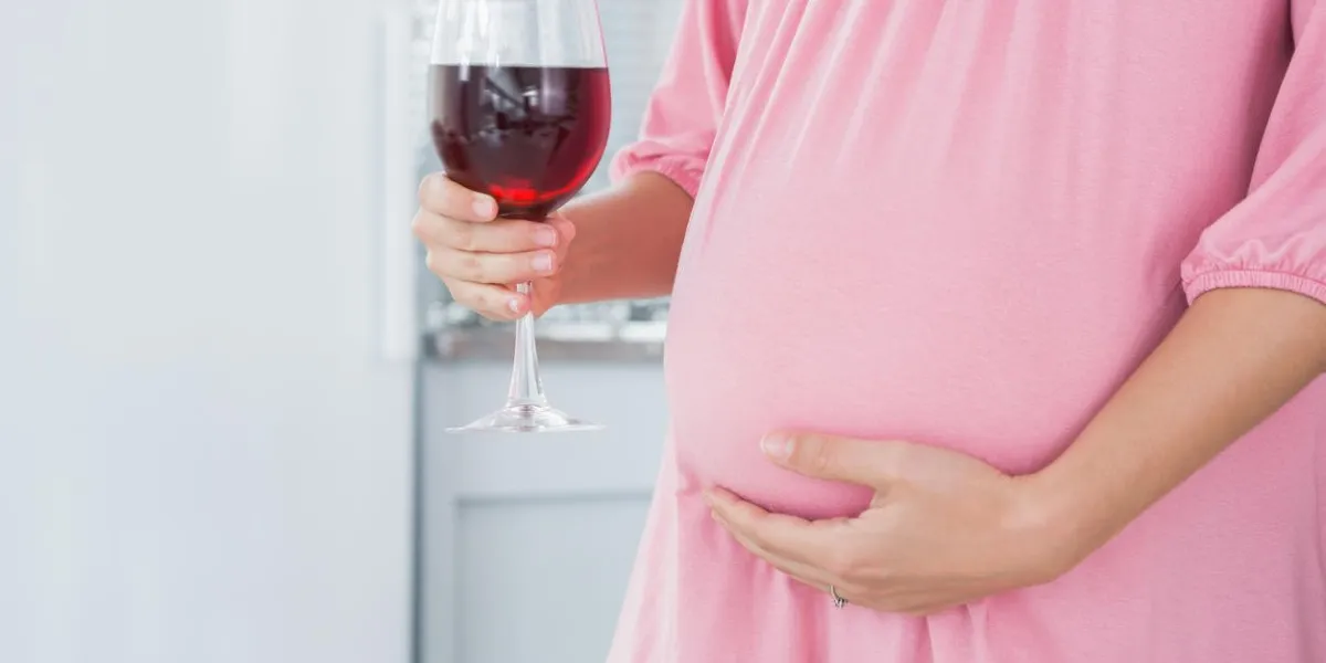 attend la femme dans sa cuisine avec du vin rouge dans la main droite