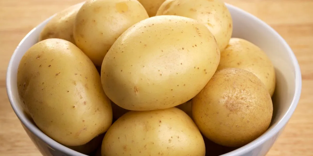 pommes de terre blanches dans un bol en porcelaine, sur une planche de bois