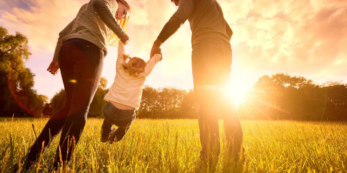 famille heureuse dans le parc lumière du soir les lumières d'un soleil maman, papa et bébé marche heureuse au coucher du soleil le concept d'une famille heureuse parents tiennent les mains du bébé