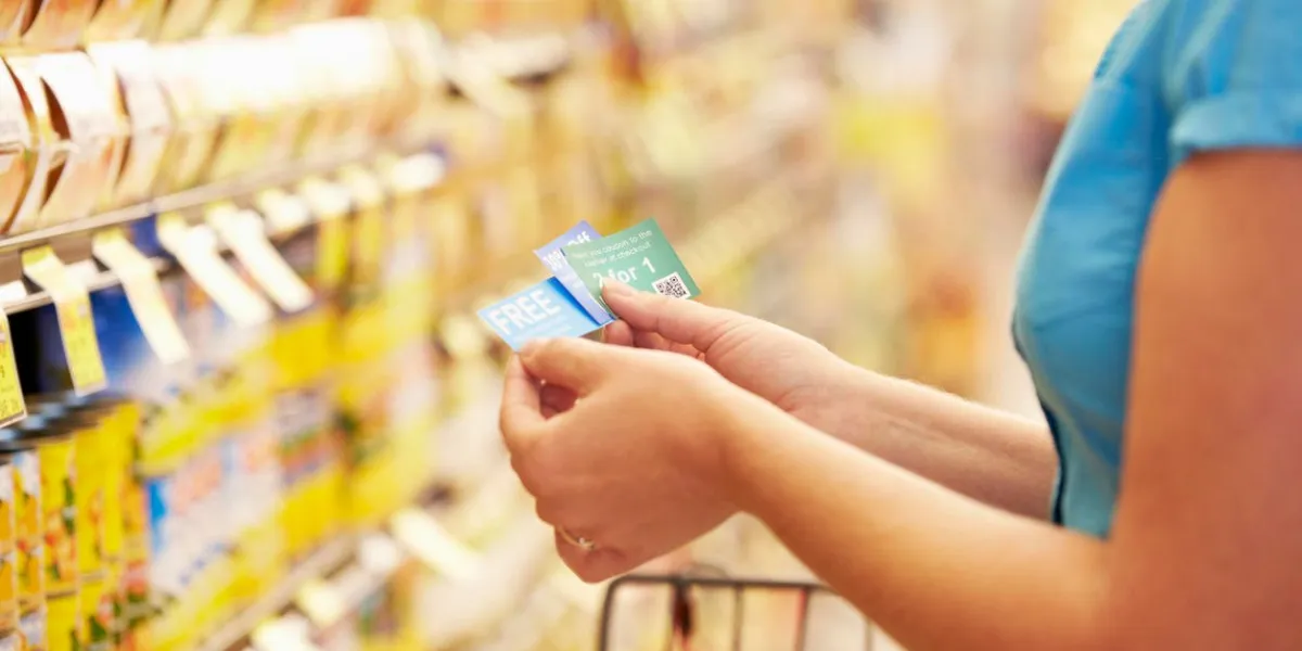woman in grocery aisle of supermarket with coupons