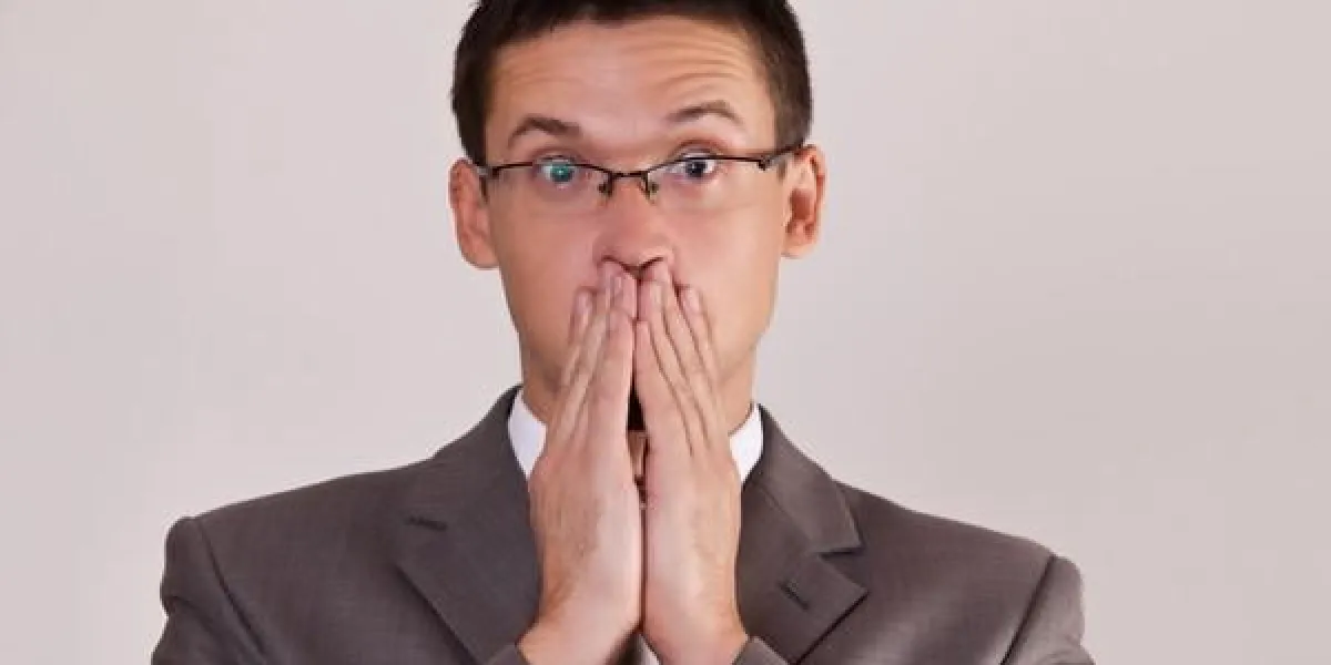 les hommes surpris ont couvert sa main de la bouche sur fond gris