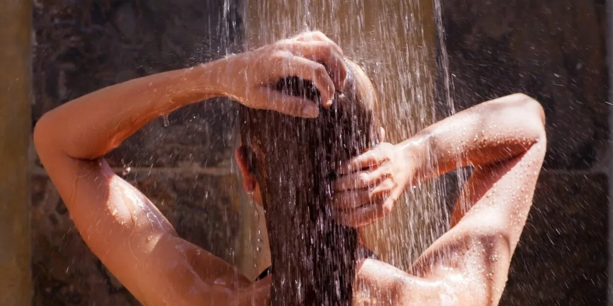 woman in the shower, back side of young female showering under refreshing water, healthy lifestyle, enjoying time in luxury spa resort