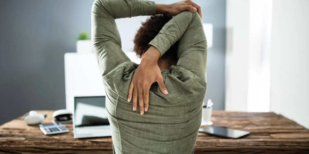 rear view of a businessman stretching his arms in office