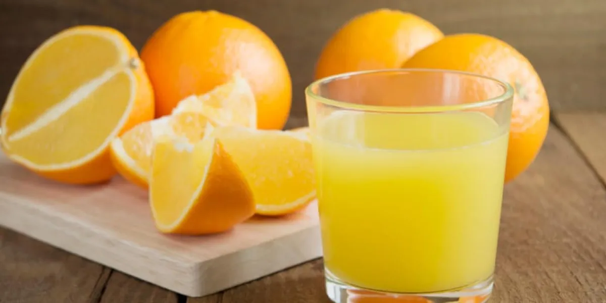 verre de jus d'orange sur un fond d'oranges et de tranches d'orange sur une table en bois