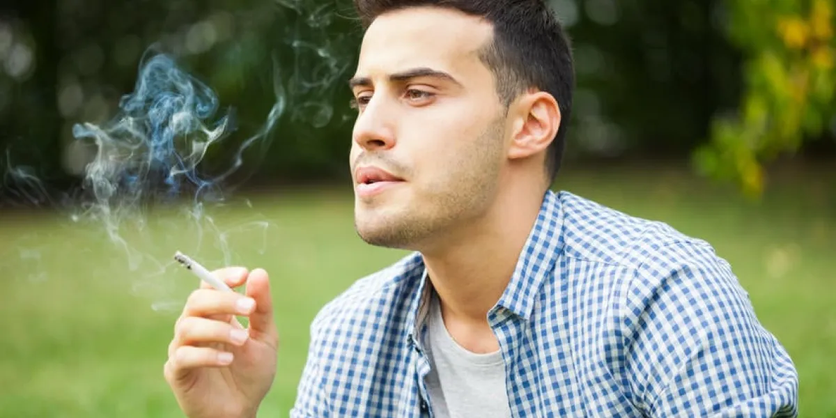 homme fumant une cigarette en plein air