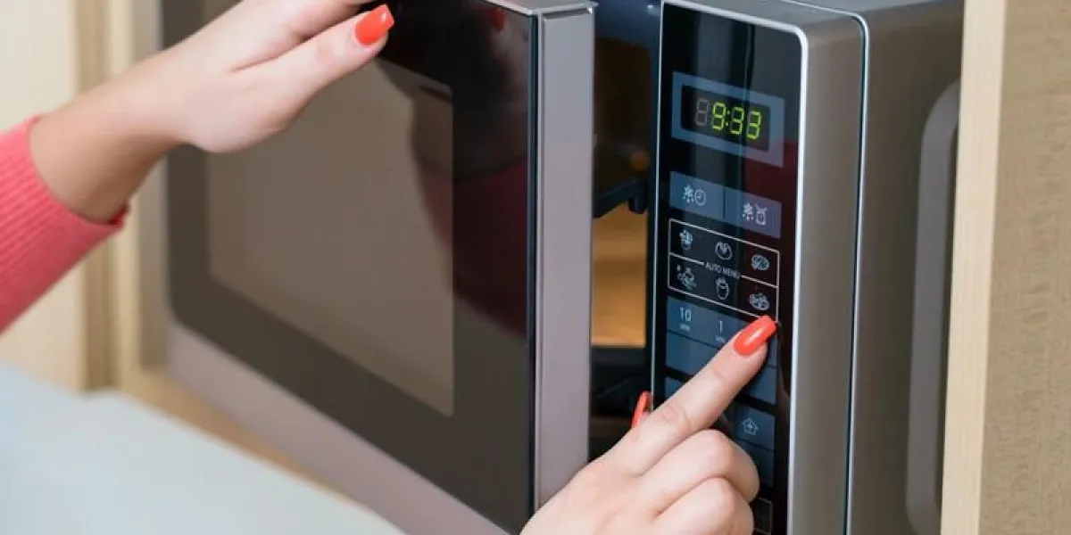 détail de la main féminine tout en utilisant le micro-ondes