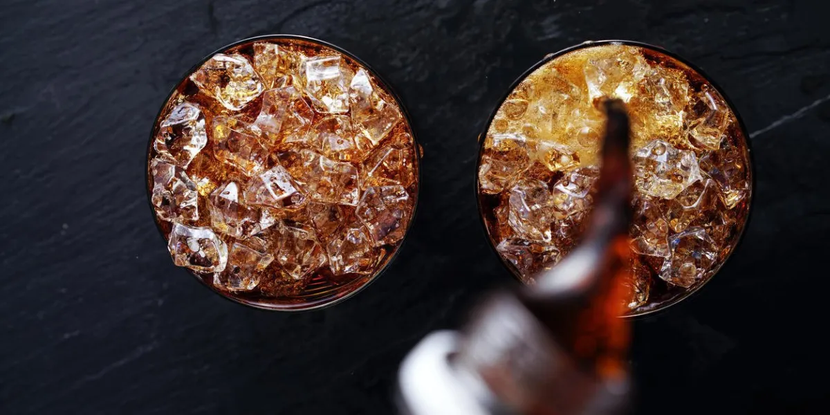 cola soda pop étant versé dans le verre avec de la glace tourné avec la composition plat