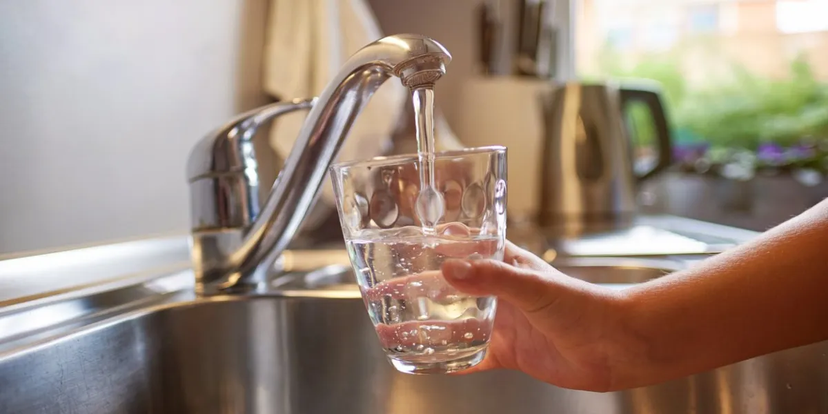 close up of children hands, pouring glass of fresh water from tap in kitchen