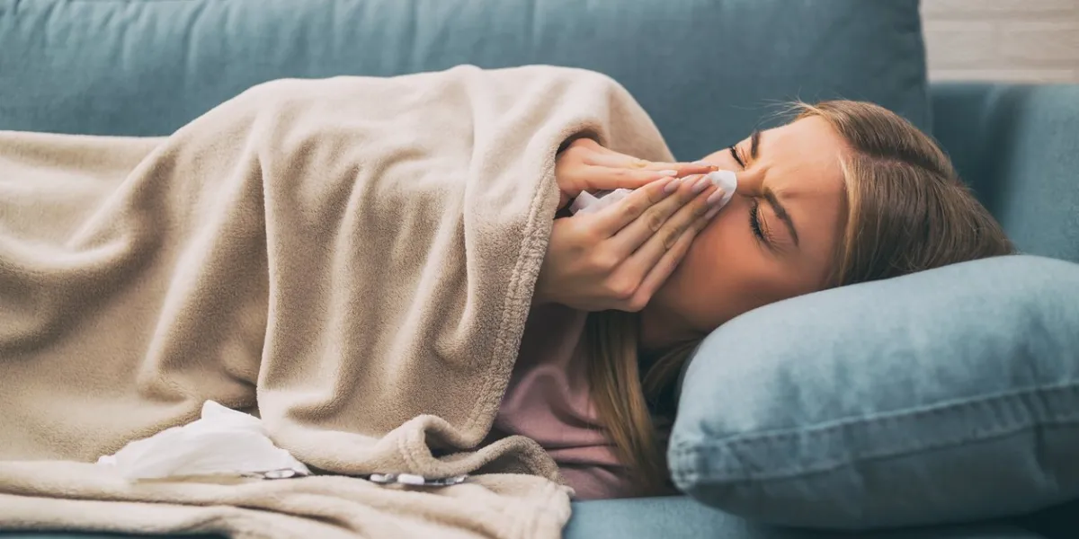 exhausted woman having fever and blowing noseimage is intentionally toned