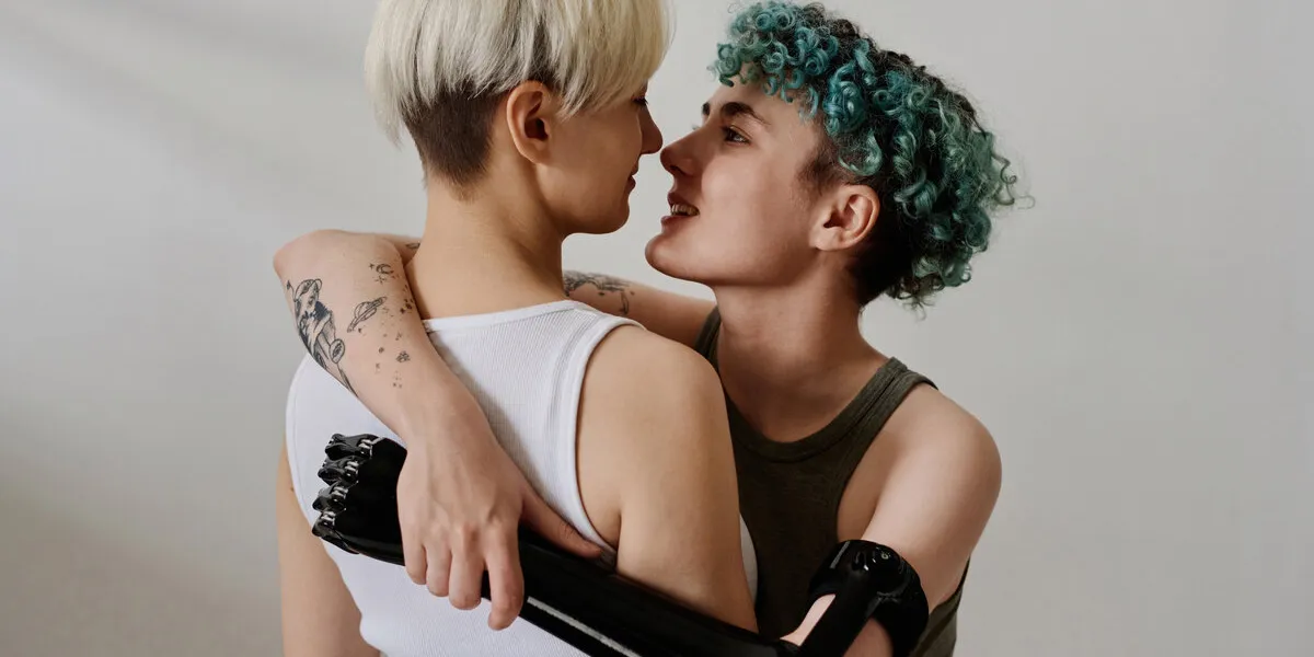 young girl with prosthetic arm embracing her girlfriend isolated on white background