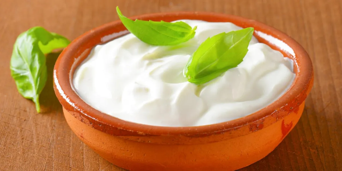 bowl of white cream on wooden table - close up