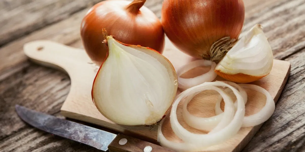 oignons frais et oignons coupés sur une planche à découper avec un couteau de cuisine