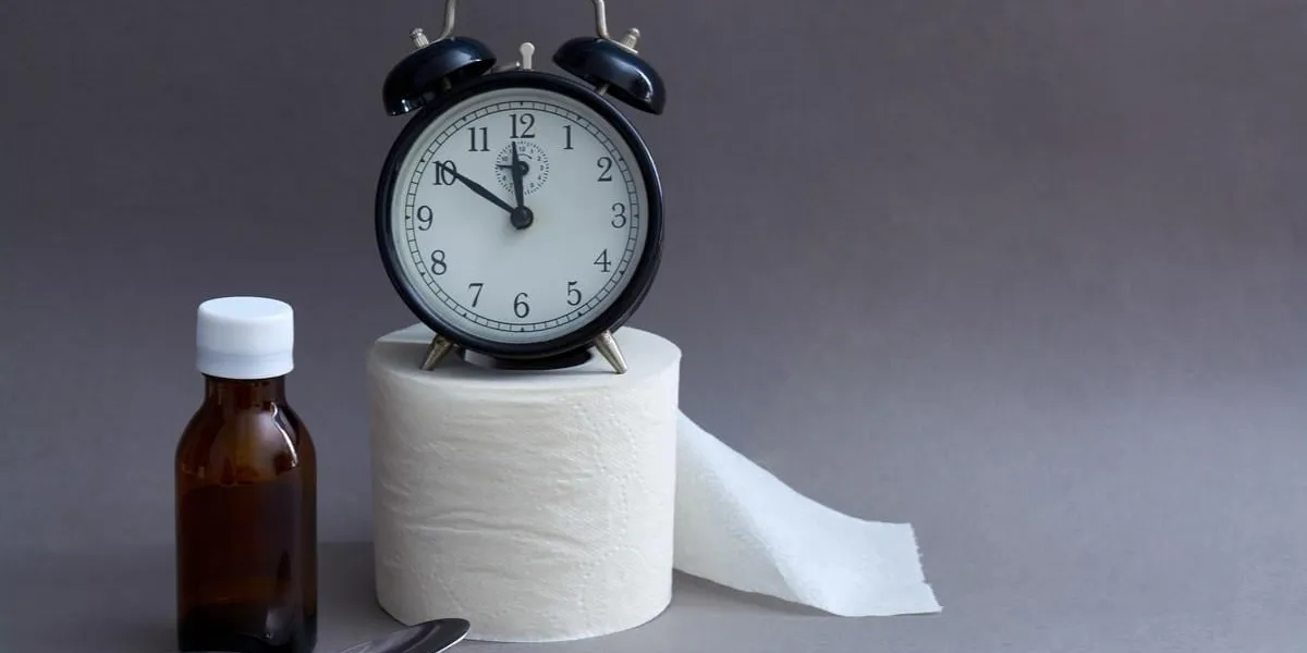 alarm clock medication and toilet paper on a dark background remedy for diarrhea