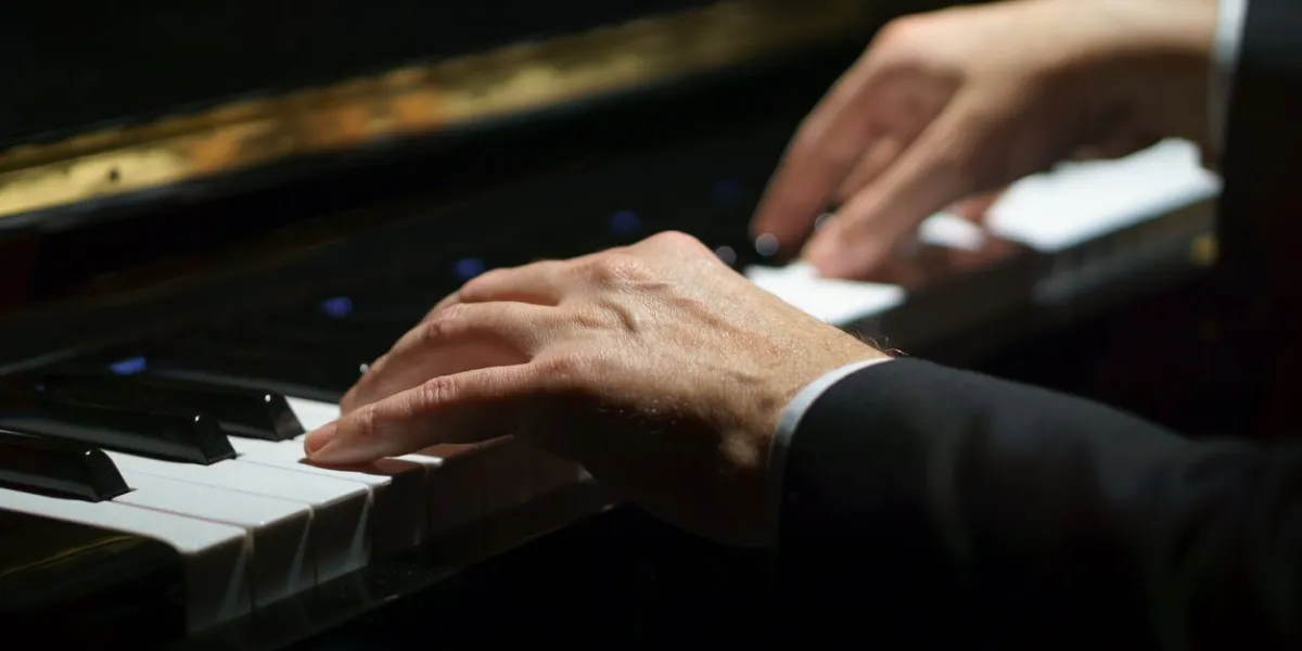 professional musician pianist hands on piano keys of a classic piano in the dark