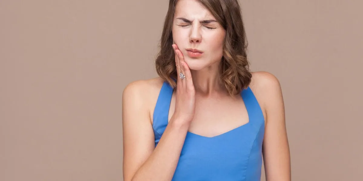 office woman closed eyes and have a dental, teeth pain studio shot, brown background