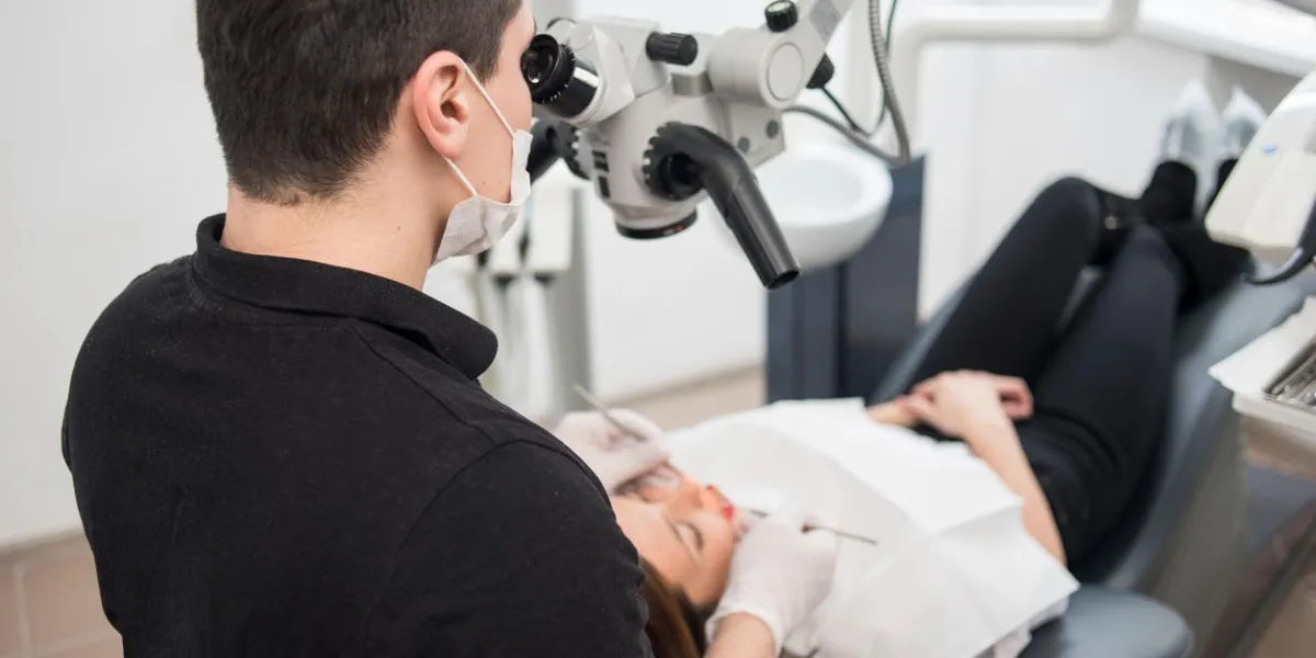 male dentist with dental tools - microscope, mirror and probe treating patient teeth at dental clinic office medicine, dentistry and health care concept dental equipment