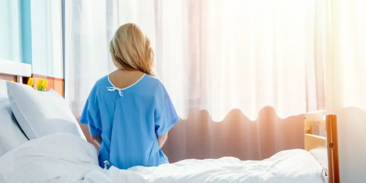 back view of woman sitting on bed in hospital chamber