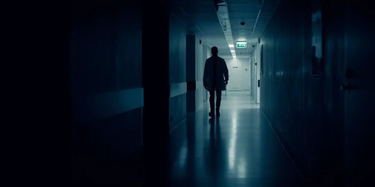 medical doctor silhouette walks in dark part of the hospital corridor