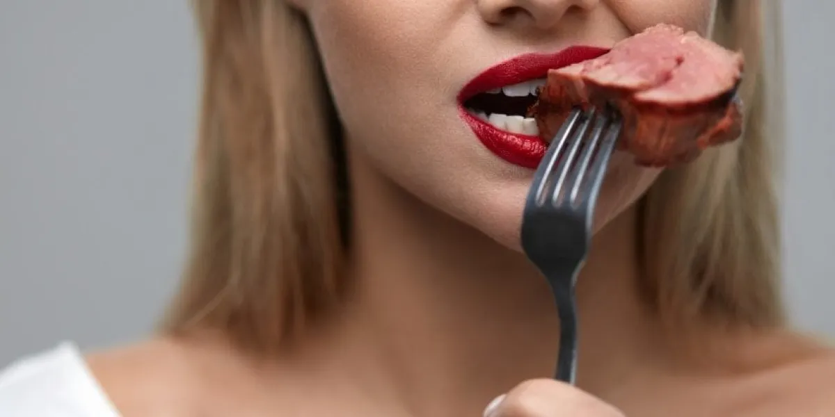 woman eating food hungry female with beautiful face, red lips eats delicious juicy grilled meat healthy girl's mouth biting slice of tasty beef steak on fork nutrition concept high resolution
