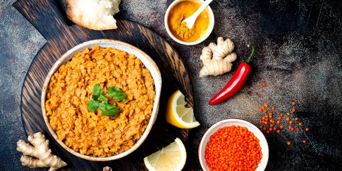 traditional red lentil dal indian dhal spicy curry in bowl with flat bread and spices top view, overhead