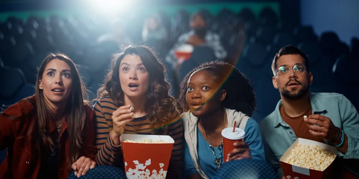 multiracial group of friends watching suspenseful movie in theater