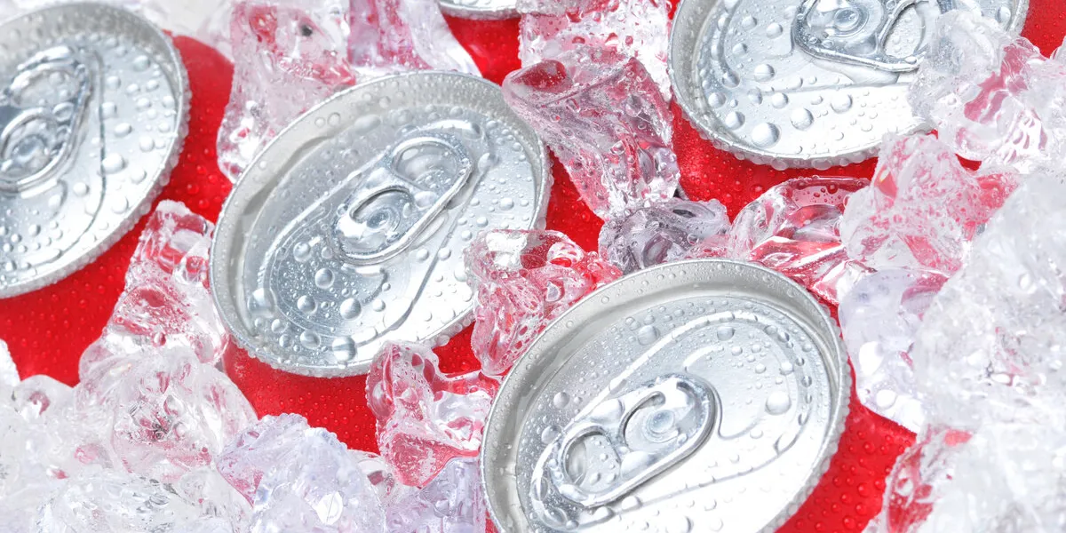 close up of soda cans in ice with condensation