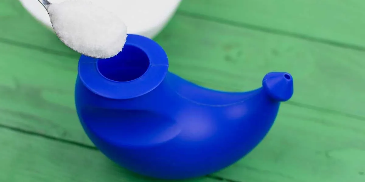 device for washing the nose near the sea salt for the preparation of a solution for washing on a green wooden background