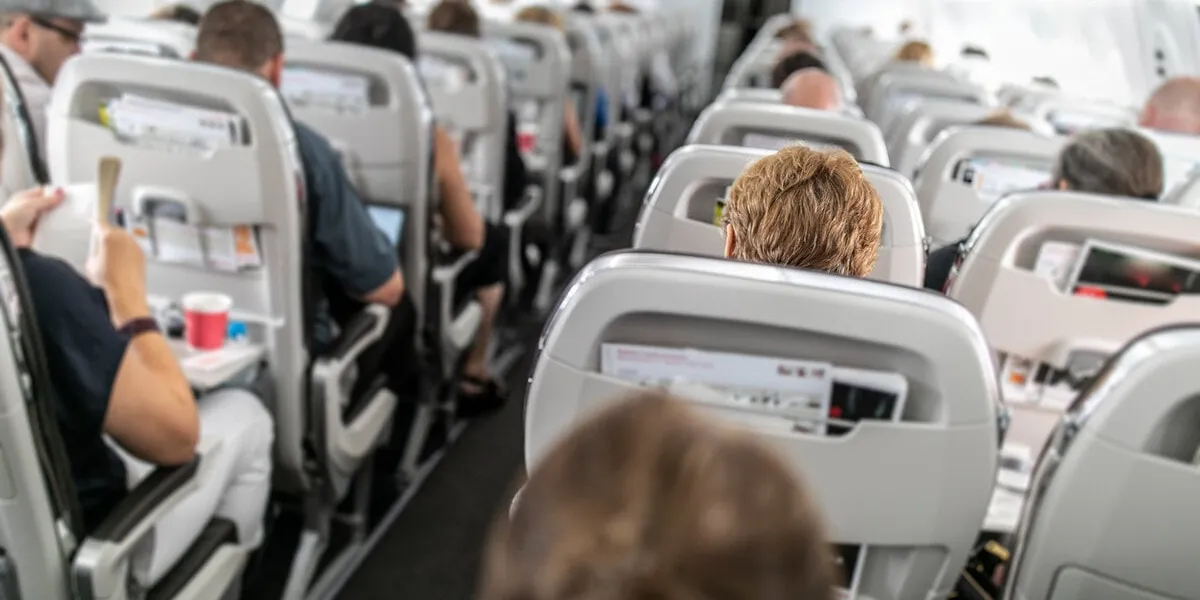 interior of commercial airplane with passengers in their seats during flight