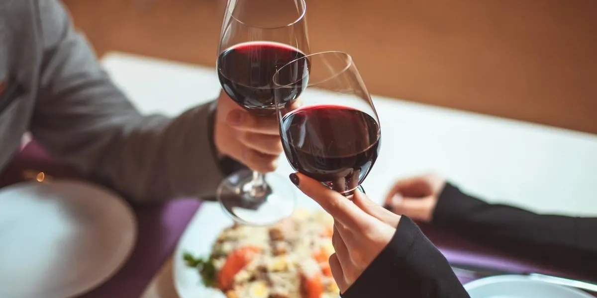 beautiful young couple with glasses of red wine in luxury restaurant