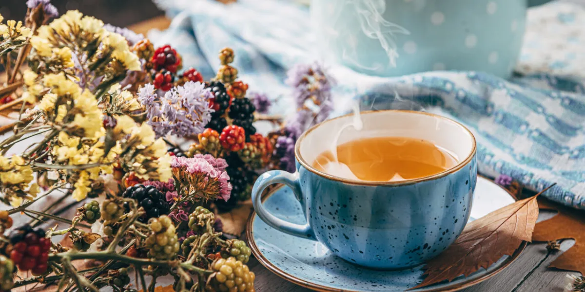 autumn warming tea on a wooden table with autumn tree leaves lying nearby
