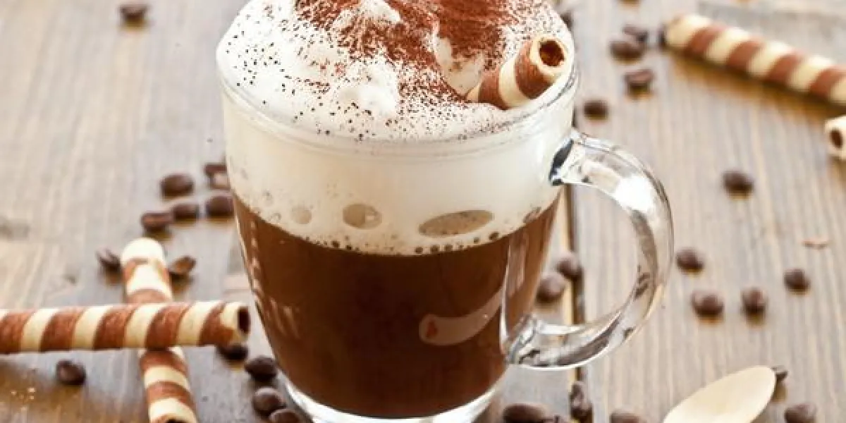 une tasse de café avec de la mousse de lait et des rouleaux de gaufres