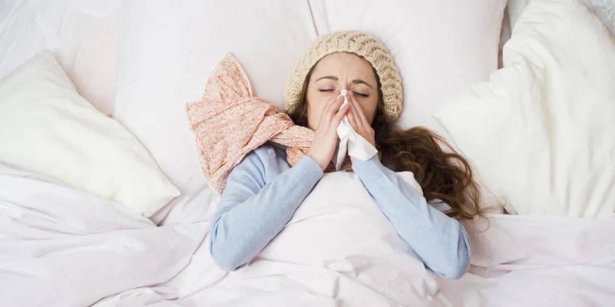 femme malade avec un thermomètre est couché dans son lit, elle a le rhume, la grippe et une forte fièvre