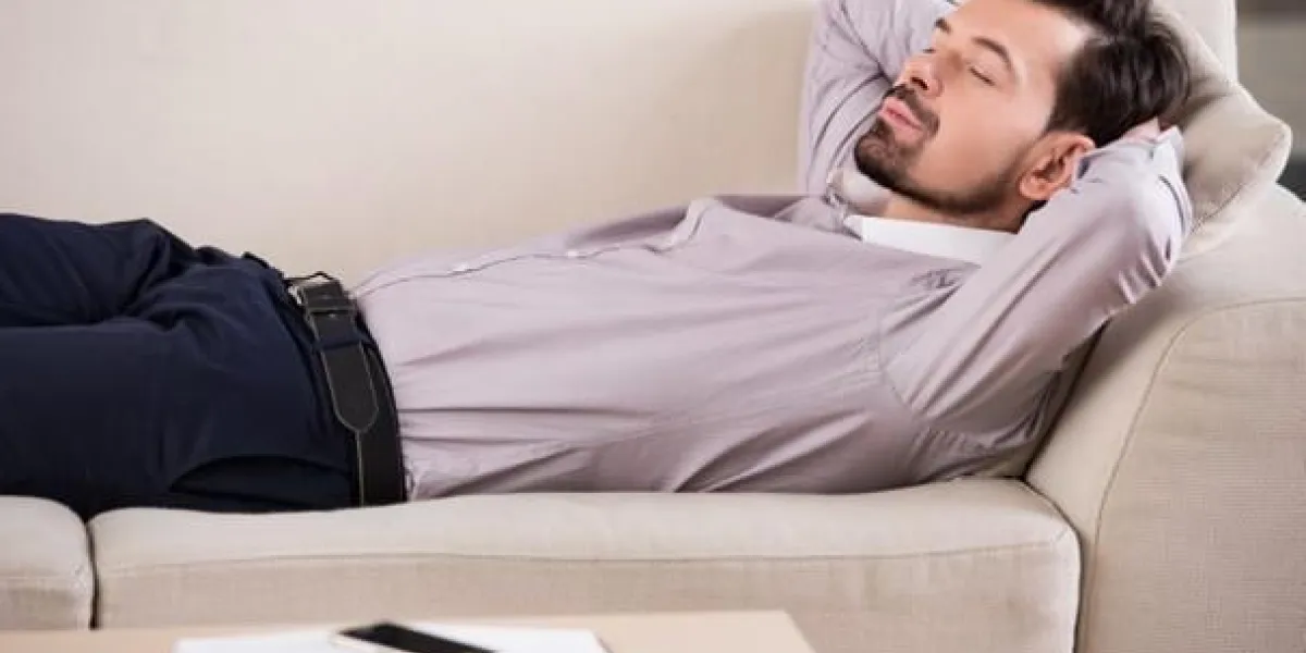 homme d'affaires fatigué dort sur le canapé au bureau